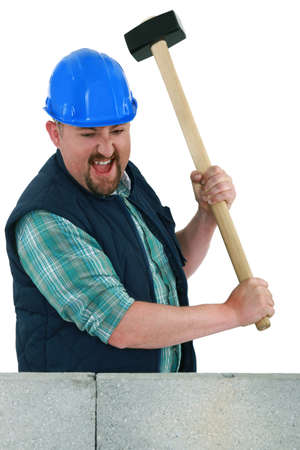 Man about to smash a wall using a malletの写真素材