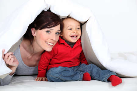 Woman and child hiding under a duvetの写真素材