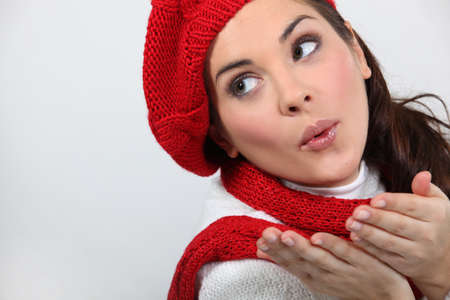 a woman wearing winter clothes is blowing a kissの写真素材