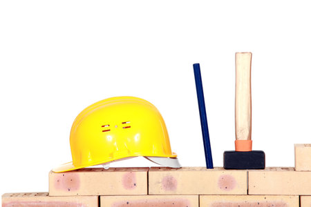 helmet, wedge and a hammer on a brick wallの写真素材