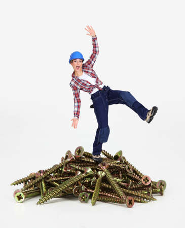 Woman balancing on pile of screwsの写真素材