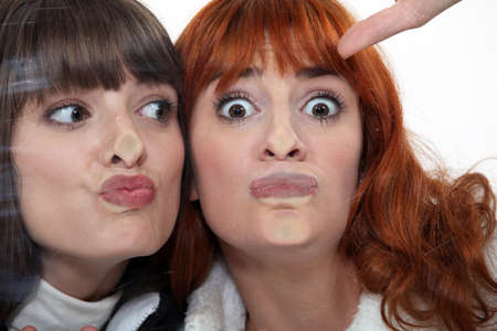 Friends making a silly face against a windowpaneの写真素材