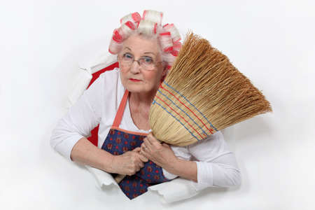 Granny with her hair in rollers holding a broomの写真素材