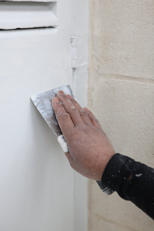 Man sandpapering wooden shutter