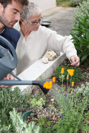 young man and older woman watering plants