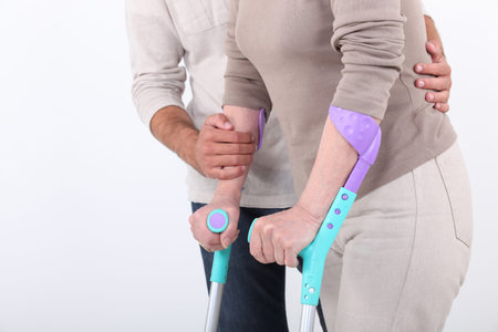 Male assistant helping a woman on crutches