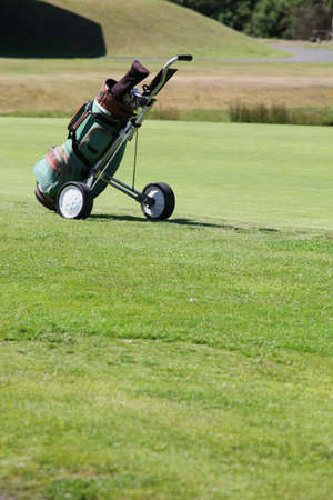 Golf bag and cart on greenの写真素材
