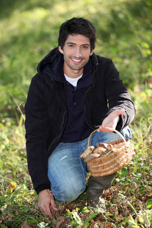 young man gathering mushroomsの写真素材