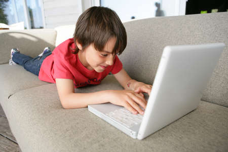 Boy using a laptop on the sofaの写真素材