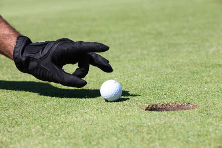 Hand placing golfball on greenの写真素材