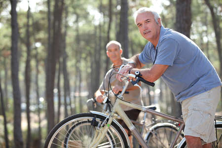 two seniors riding bikes in the parkの写真素材