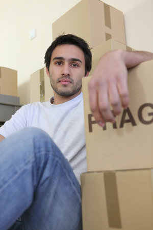 Young man surrounded by cardboard boxes on moving day