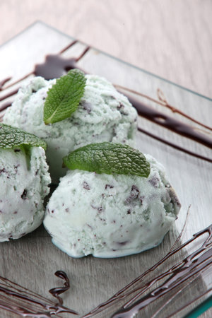 Three balls of mint chocolate chip ice cream on a square glass platterの写真素材