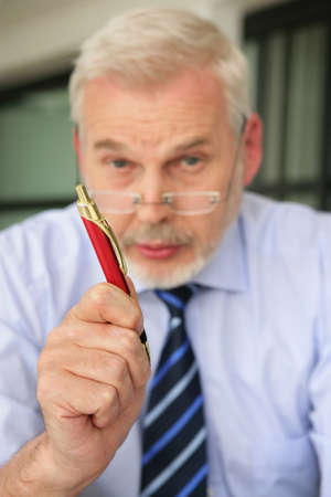 Senior man gesturing with penの写真素材