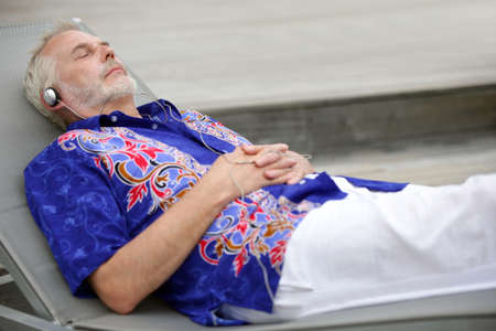 Senior man in seat listening to musicの写真素材