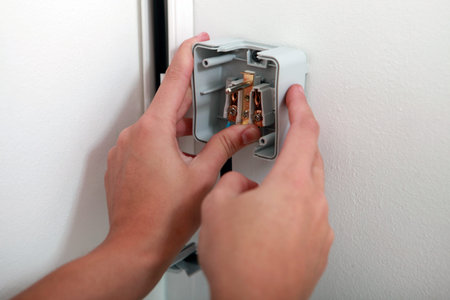 electrician attaching electrical outlet to wall
