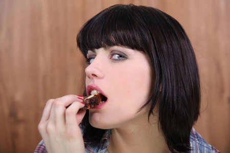 Brunette woman eating slice of chocolateの写真素材
