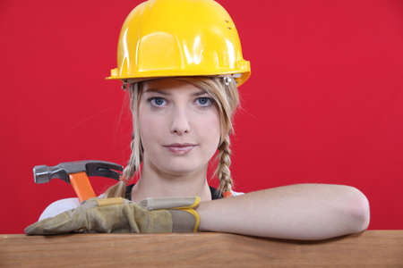Woman in a hard hat holding a hammerの写真素材