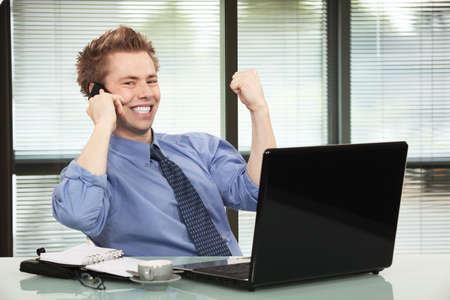 Happy businessman hearing good news on phoneの写真素材