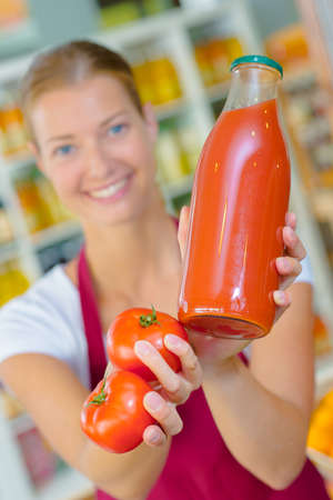 Woman holding a bottle of tomato juiceの写真素材