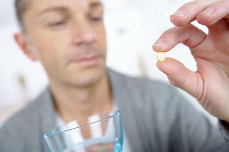 Man taking a tablet with a glass of waterの写真素材