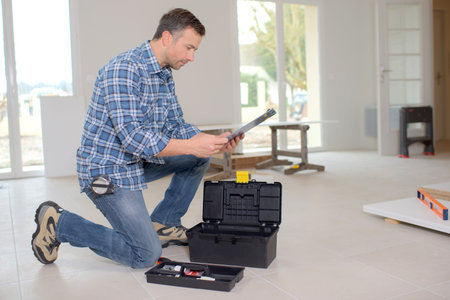 Builder kneeling by his toolboxの写真素材