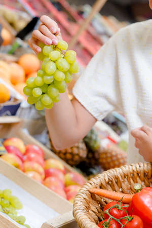 Woman choosing a bunch of grapesの写真素材
