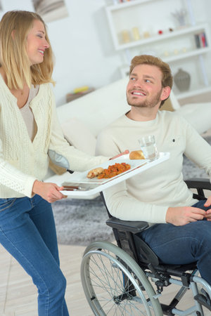 Boyfriend in wheelchair about to have lunchの写真素材