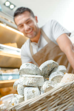 Shop assistant with basket of cheesesの写真素材