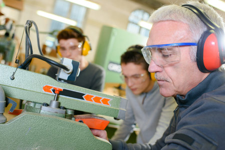 Experienced carpenter teaching two teenage boys
