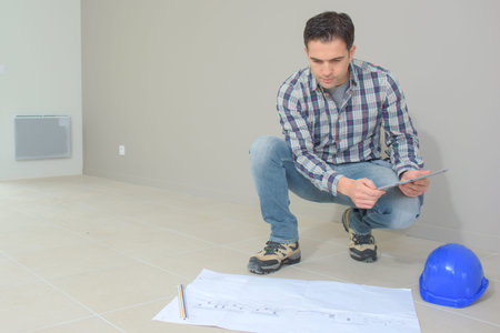 Builder kneeling down by plans