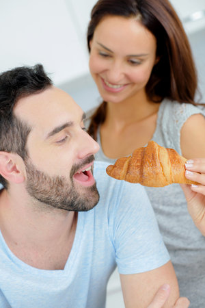 Romantic couple sharing a croissantの写真素材