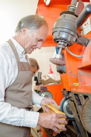 Cobbler using machinery on heel of shoe