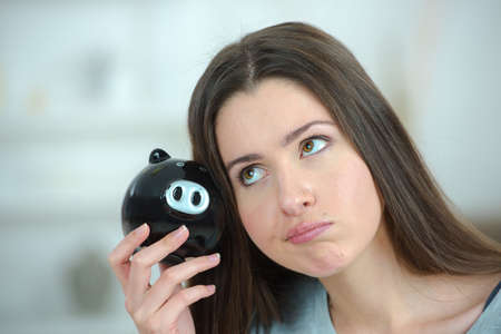 Woman putting coin into a piggy bankの写真素材