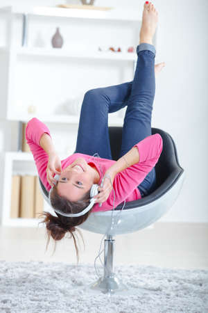 woman listening to headphones whilst on a chairの写真素材