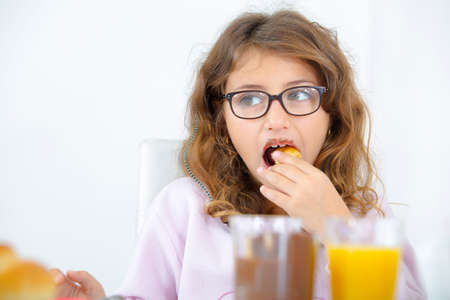 Little girl having her breakfast in the kitchenの写真素材