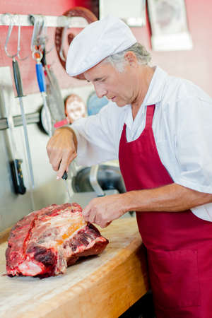 Butcher working on a large cut of beefの写真素材