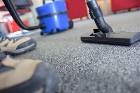 Closeup of male feet and vacuum cleanerの写真素材