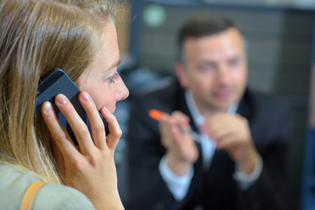 Lady on mobile phone, suited man blurred in background