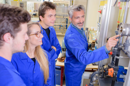 Teacher pointing to machine, everyone smiling