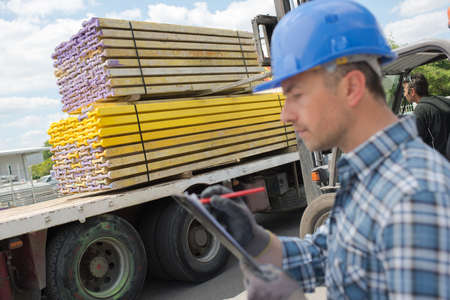 Man in hardhat checking clipboardの写真素材