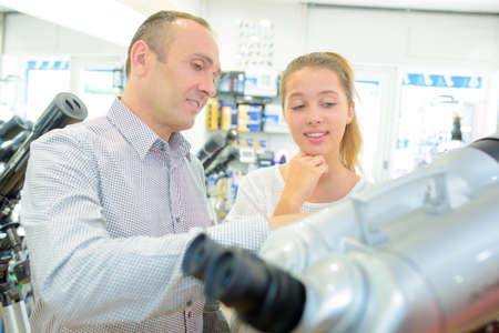 Young lady looking at binoculars with middle aged manの写真素材