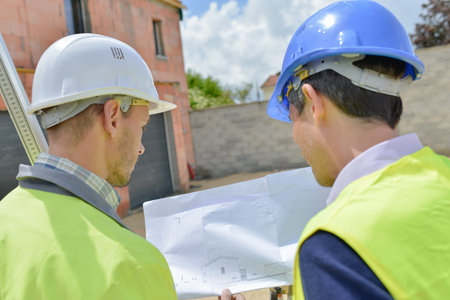 Two men on building site looking at plans