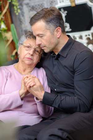 Man comforting elderly womanの写真素材
