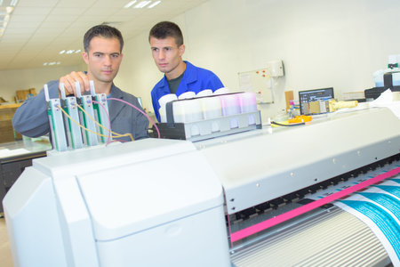 Man adjusting ink cartridges on professional printing machine