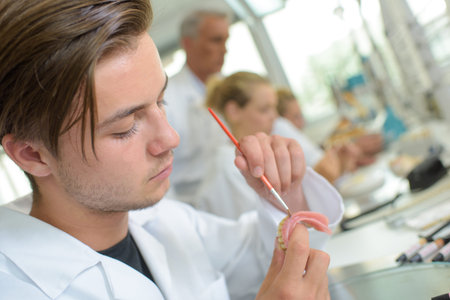 Young man manufacturing false teeth