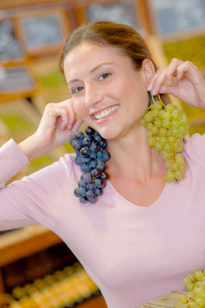 Funny woman holding grapes as earringsの写真素材
