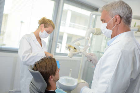 Dentist and assistant with male patientの写真素材