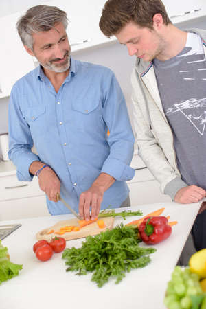 Man preparing vegetables, younger man looking on dubiouslyの写真素材