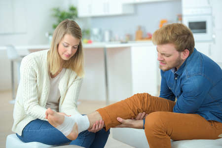 Girlfriend putting a bandage on his legの写真素材